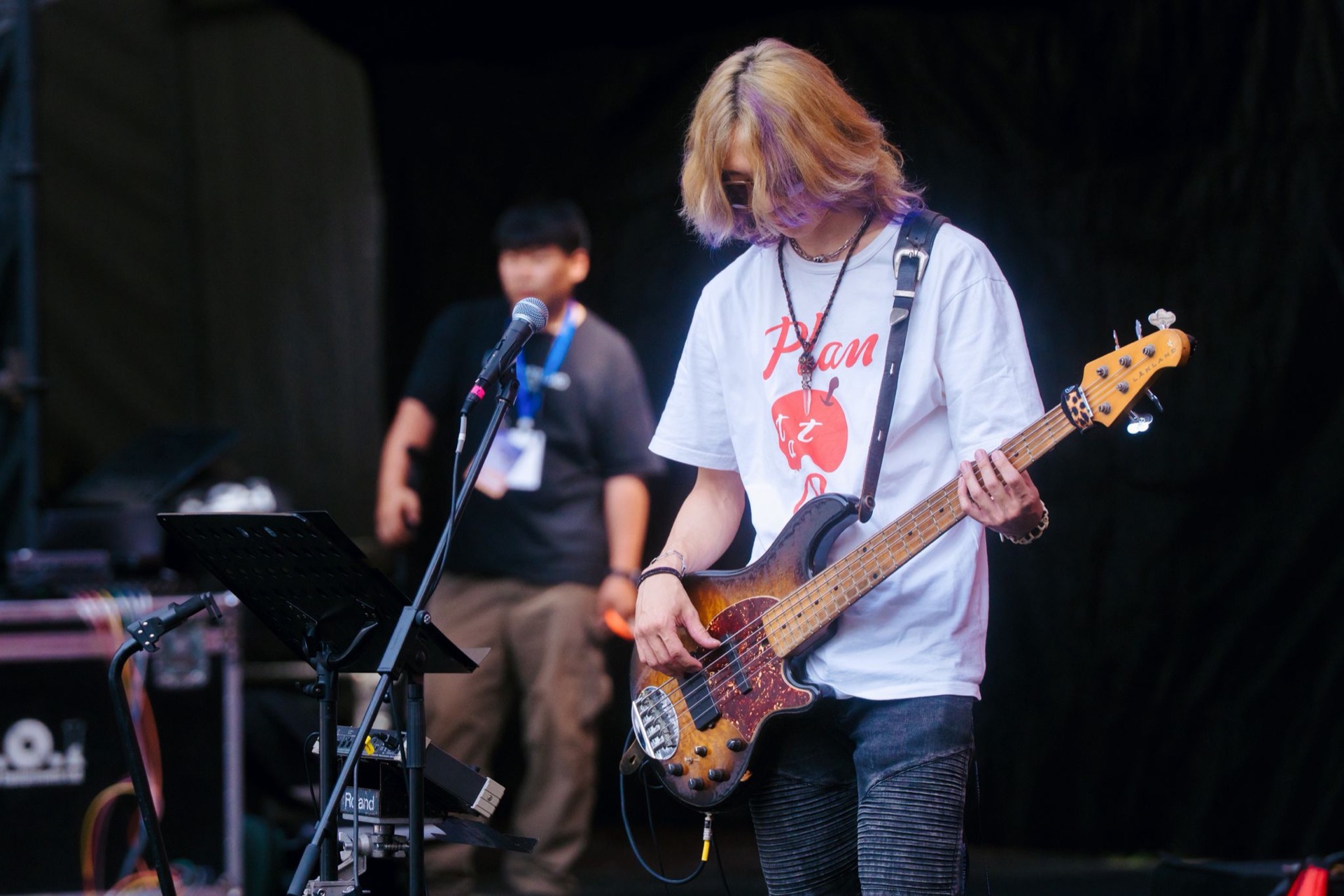 Sasha Wu playing a five-string electric bass on stage